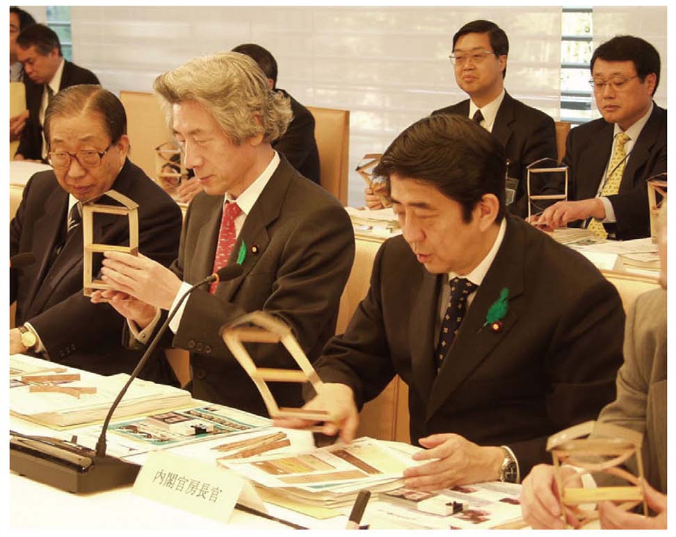 写真9　第17回中央防災会議　耐震教材を手にする安倍内閣官房長官（当時）