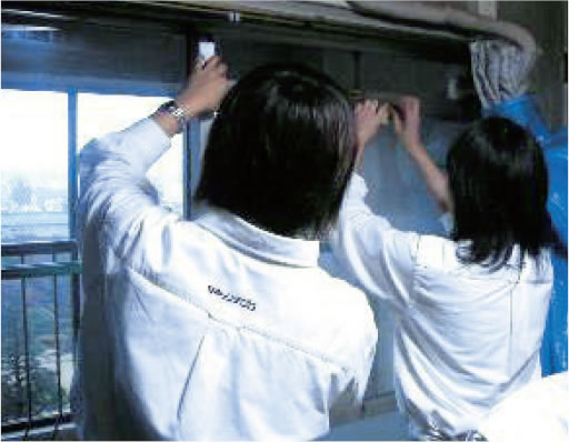 早稲田地区における防災まちづくり活動：高齢者の住宅にガラス飛散防止フィルム貼りを支援する写真