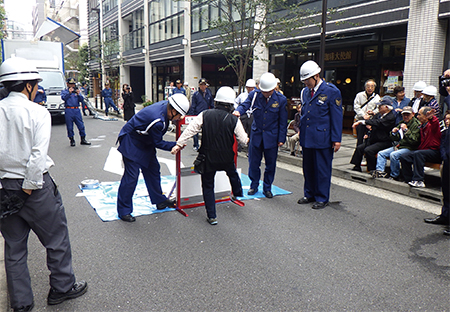 地元町会との合同防災訓練では「ベランダ仕切り板蹴破り体験」（写真左）