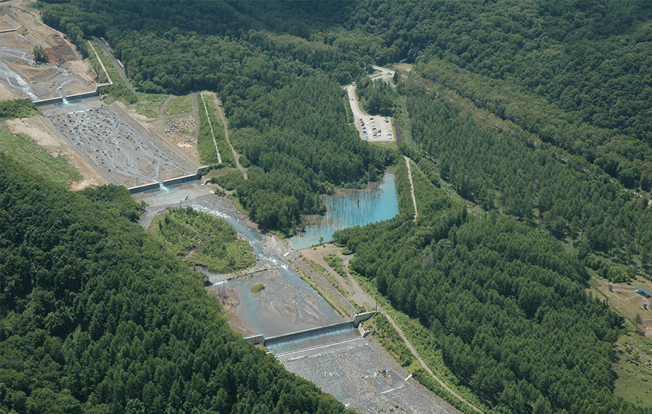 美瑛川を上空から見た様子。川底や川岸の侵食を防ぐもの、大きな岩や流木を止めるものなど、さまざまな砂防施設が整備されています。（出典：国土交通省北海道開発局旭川開発建設部）