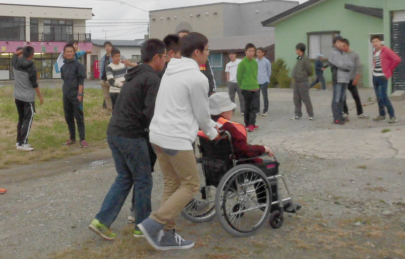 防災教育プログラムとして行われる避難訓練で、車椅子の高齢者の移動を助ける高校生（写真提供：奥尻町）
