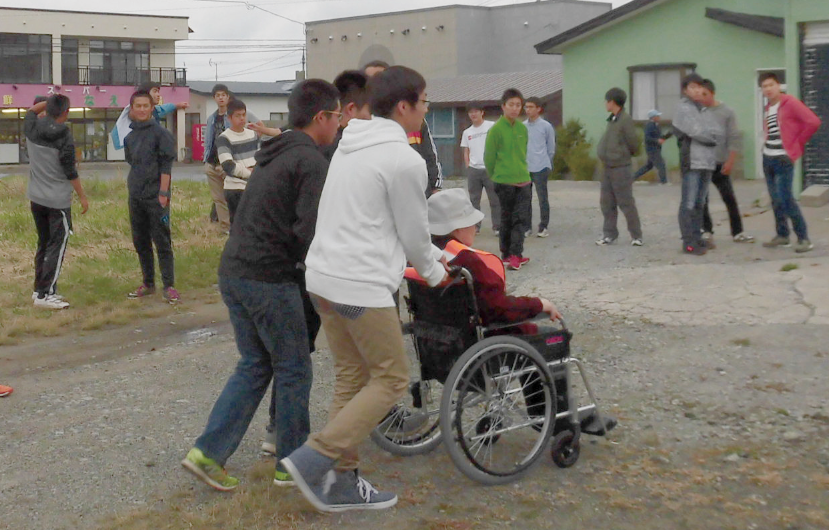 防災教育プログラムとして行われる避難訓練で、車椅子の高齢者の移動を助ける高校生(写真提供:奥尻町)