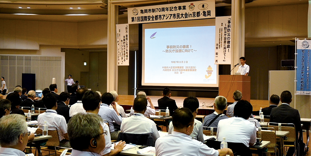 写真1 内閣府河合審議官による基調講演（令和7年（2025年）8月2日撮影）