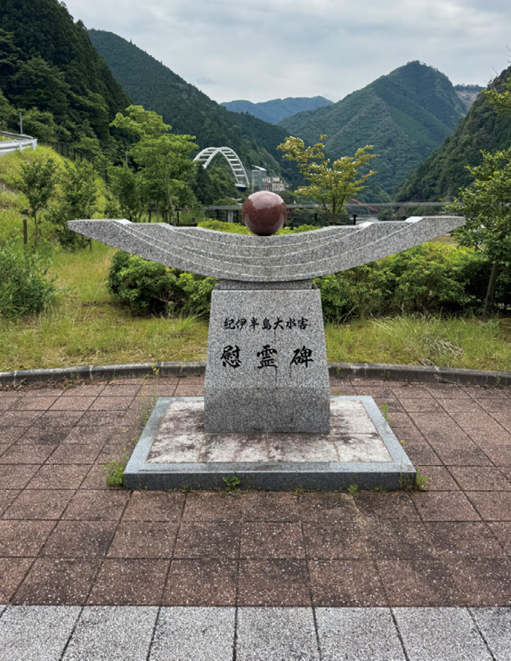 慰霊碑が建てられた五條市大塔町宇井地区の広場からは崩壊斜面の跡を見ることが可能（令和8年（2026年）6月撮影）